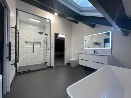 uma casa de banho com um chuveiro, um lavatório e um espelho. em The clubhouse em Hamilton