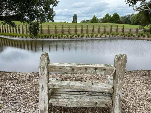 an old wooden bench sitting in front of a pond at The clubhouse in Hamilton