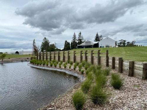 a fence next to a river with a house in the background at The clubhouse in Hamilton