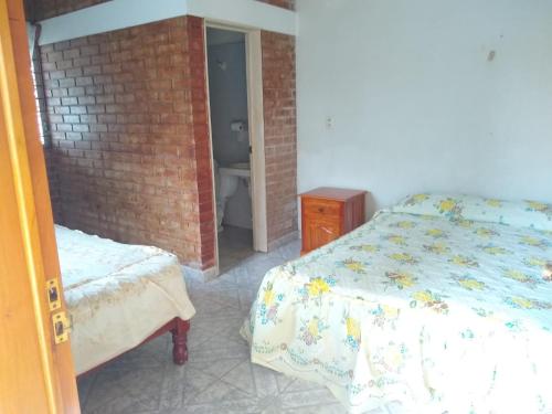 a bedroom with a bed and a brick wall at CASA EL DELFÍN ROSADO in Tecolutla