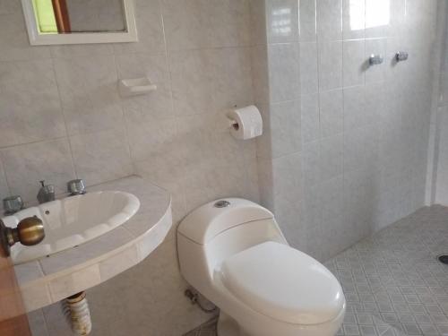a white bathroom with a toilet and a sink at CASA EL DELFÍN ROSADO in Tecolutla
