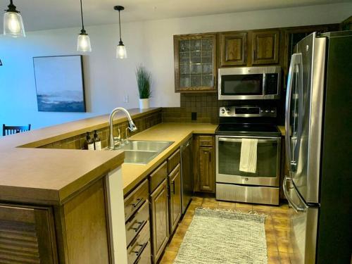 una cocina con electrodomésticos de acero inoxidable y armarios de madera en Beaver Creek/Avon condo on lake with BC ski views, en Avon