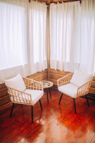 two chairs and a table in a room with white curtains at Jaguar Creek in Good Living Camp