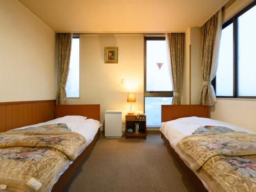 Cette chambre comprend 2 lits et une fenêtre. dans l'établissement Tabist Business Ryokan Hotel Yukimiso, à Toyama
