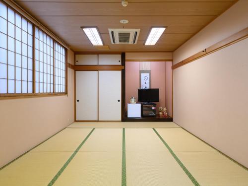 an empty room with a door and a tv at Business Ryokan Hotel Yukimiso in Toyama