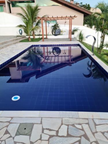 a swimming pool with blue water in front of a house at Casaazulvaleparaiba in Jacareí
