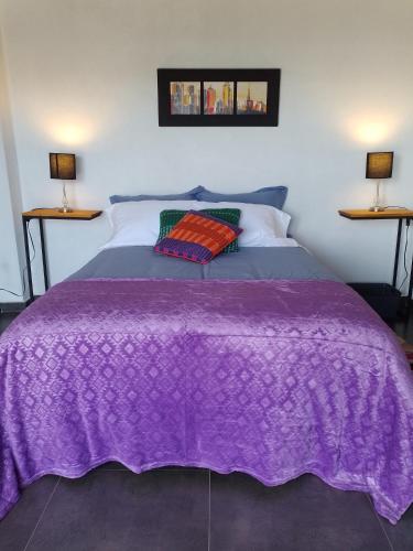 a purple blanket on a bed with two lamps at Casablanca Choachi in Choachí