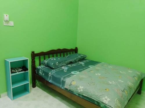 a green bedroom with a bed and a night stand at PCB PURPLE GUEST HOUSE in Kota Bharu