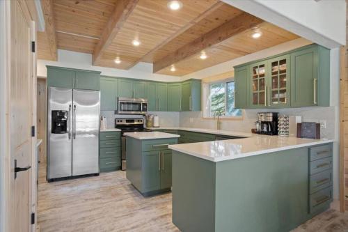 una cucina con armadi verdi e frigorifero in acciaio inossidabile di New Modern Cabin w fireplace Hot Tub Sleeps 12 a Donnelly