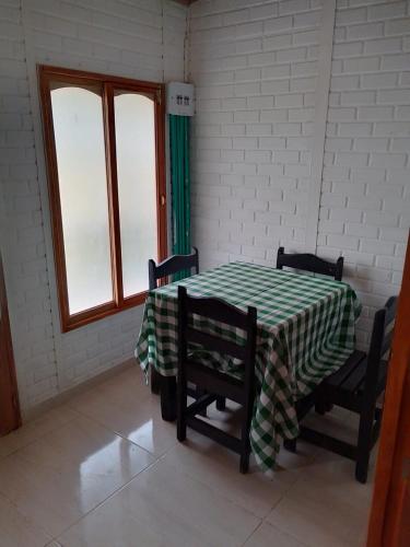 Habitación con mesa, 2 sillas y 2 ventanas en Acogedoras - Cabañas Villa Paty, en Santa Rosa de Cabal
