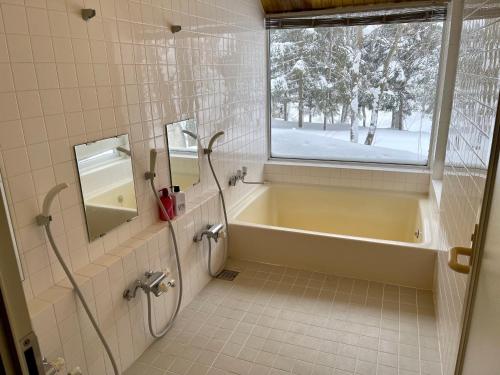 baño con bañera y ventana en 19 Accommodation, en Hachimantai