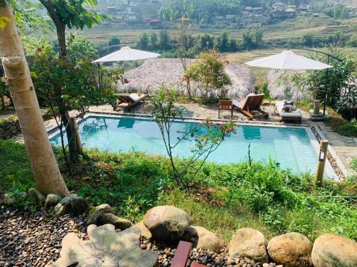 een zwembad in een tuin met parasols bij Sapa Eco Bungalows & Spa in Sa Pa