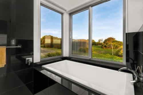 a white bath tub in a bathroom with windows at The Point Bass Coast in Bass