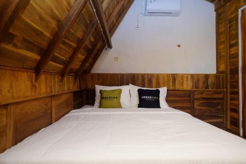 1 dormitorio con 1 cama con sábanas y almohadas blancas en Urbanview Villa Lukulo Kebumen by RedDoorz, en Kebumen