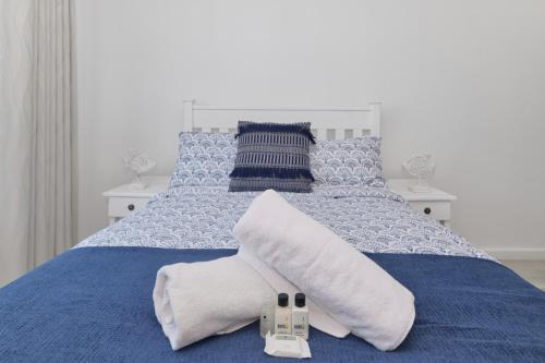 a blue bed with two towels and two remotes on it at Beachcombers in Agulhas