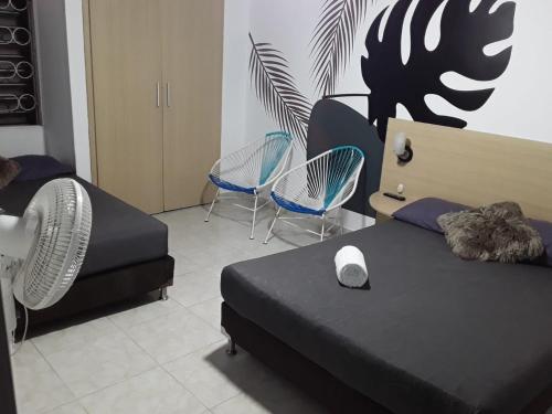 een slaapkamer met 2 bedden en stoelen en een ventilator bij Primavera Hotel in Medellín