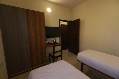 a room with two beds and a desk and a mirror at Elysian Grand Hotel in Bengaluru