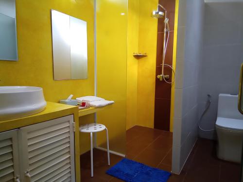 a yellow bathroom with a sink and a shower at Koh Ker Temples Garden Hotel and Restaurant in Phumĭ Mréch