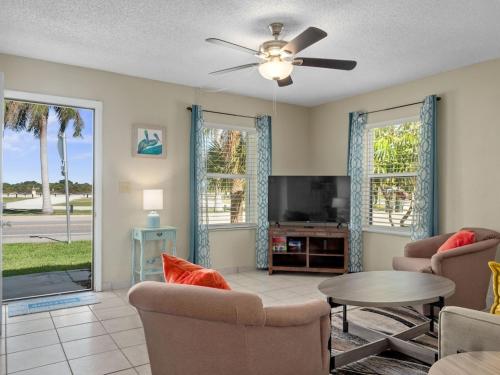 a living room with a ceiling fan and a tv at Island-Life! A in Fort Pierce