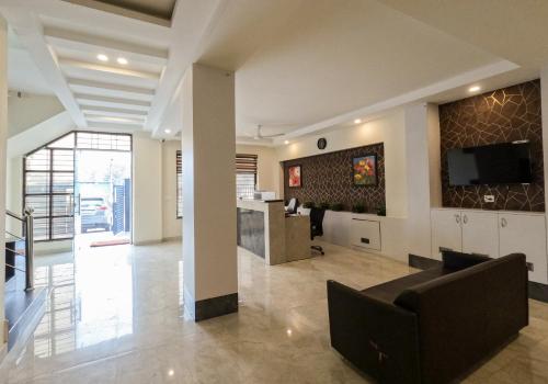 a living room with a couch and a tv on a wall at Hotel The Luxem - Behind Ibis Hotel Gurugram in Gurgaon