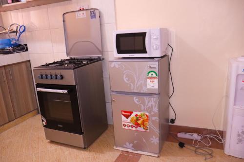 a microwave sitting on top of a refrigerator next to a stove at Vush Homes in Nairobi
