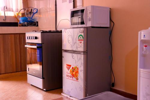 a microwave sitting on top of a refrigerator in a kitchen at Vush Homes in Nairobi