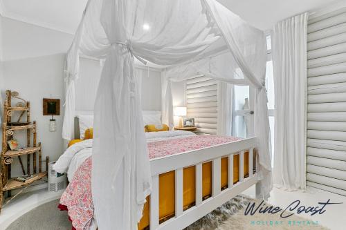 a white canopy bed in a white bedroom at Sea Gypsy by Wine Coast Holiday Rentals in Aldinga Beach