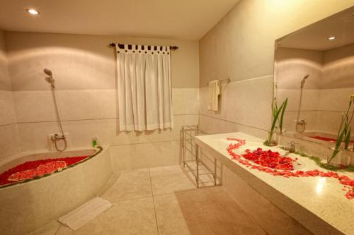 a bathroom with a tub and a sink with red flowers at Warung Mandi & Villa in Ubud