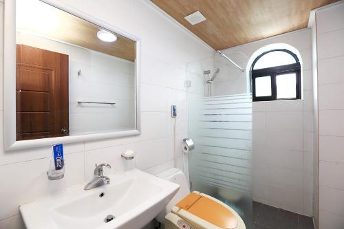 een badkamer met een wastafel, een toilet en een spiegel bij Sea View in Jeju-stad