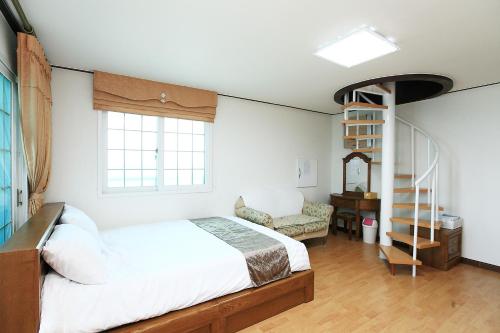 濟州的住宿－Sea View，卧室设有白色的床和螺旋楼梯。