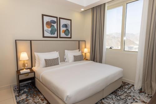 a bedroom with a large white bed and two windows at Platinum Coast Hotel Apartments in Fujairah