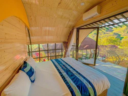 Cama en habitación con ventana grande en Plum Homestay, en Dồng Văn