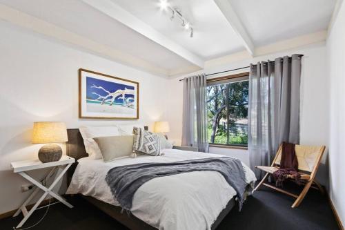 a white bedroom with a bed and a window at Fairview Lakeside Cottage Metung in Metung