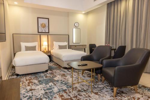 a hotel room with two beds and a table and chairs at Platinum Coast Hotel Apartments in Fujairah