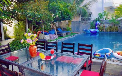 una mesa y sillas junto a una piscina en Hoi An Mountain House Villa, en Hoi An