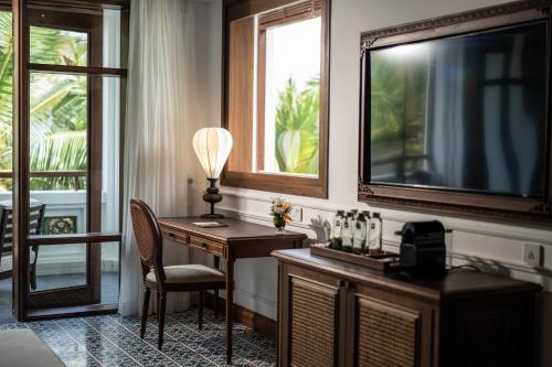 a room with a desk and a television and a chair at The Anam Mui Ne in Mui Ne