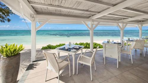 a white table and chairs on a patio with the beach at Holiday Inn Mauritius Mon Trésor by IHG in Blue Bay