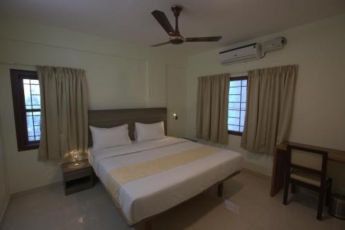 Elysian Grand Hotel في بانغالور: غرفة نوم بسرير ومروحة سقف