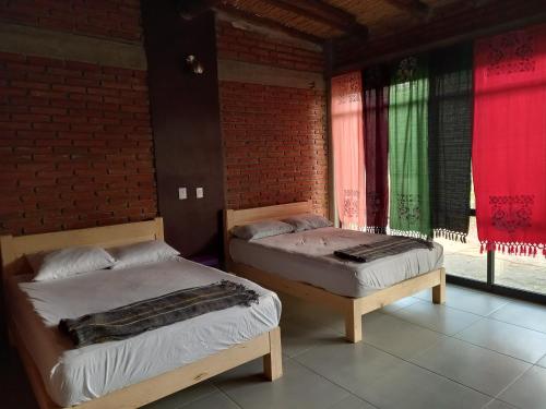 two beds in a room with a brick wall at Casa Ejutla de Crespo, Oaxaca 