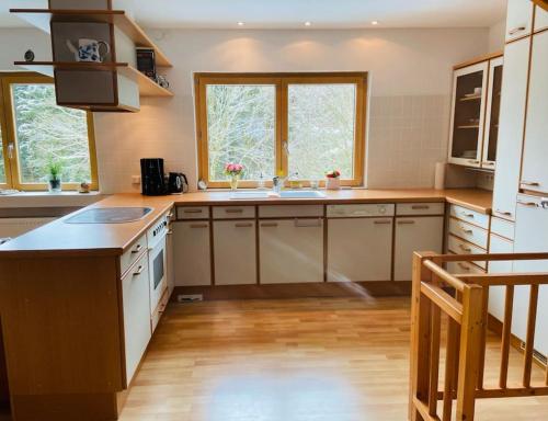 una cocina con electrodomésticos blancos y suelos y ventanas de madera. en Hundeparadies Waldblick Lauenstein, en Ludwigsstadt