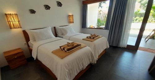 two beds in a hotel room with towels on them at Blue Marlin Air in Gili Islands