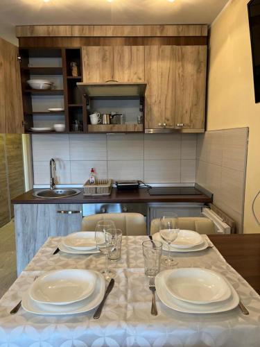 a kitchen with a table with plates and wine glasses at Apartman ML in Raška