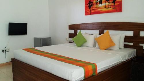 een slaapkamer met een groot wit bed met kleurrijke kussens bij Maple Leaf Resort in Negombo