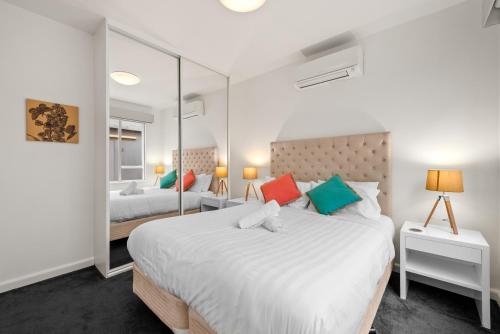 1 Schlafzimmer mit 2 Betten und einem großen Spiegel in der Unterkunft StayCentral - Brunswick Vibe Parkville in Melbourne