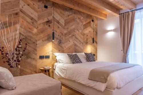 a bedroom with a wooden accent wall and a bed at B&B El Lares - B&B L'Avez in Canale dʼAgordo