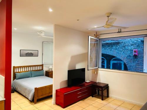 um quarto com uma cama, uma televisão e uma janela em Céntrico apartamento a 150 metros de la playa. Parking* em Lloret de Mar