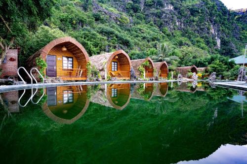 a group of cottages with their reflections in the water at THE GOAT BOUTIQUE RESORT in Ninh Binh