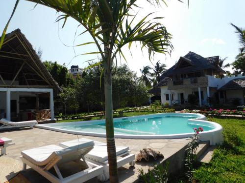 a pool with a palm tree and two lounge chairs at Dama Villa in Watamu