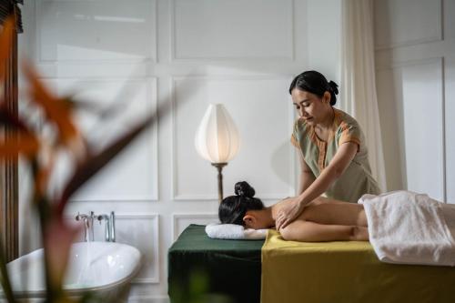a woman laying on a bed with a woman getting a massage at The Anam Mui Ne in Mui Ne