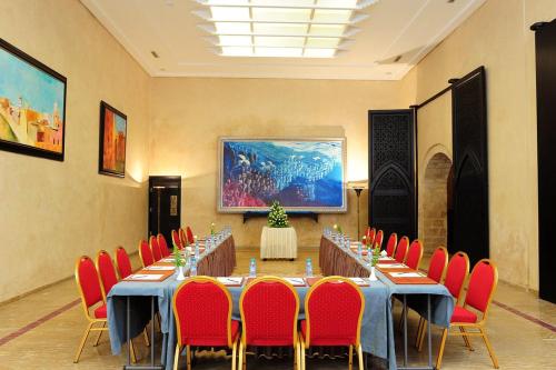 a meeting room with long tables and red chairs at Art suites in El Jadida